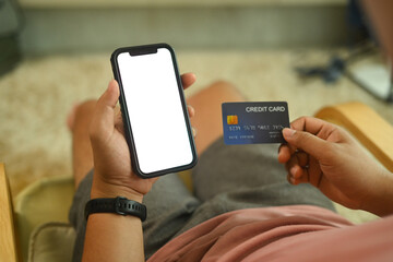 Close up shot of man holding a credit card and purchasing online on smartphone