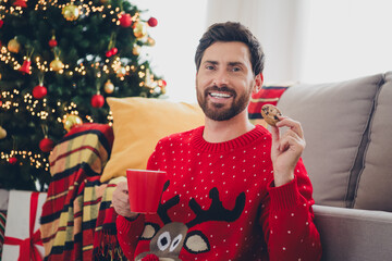 Canvas Print - Photo of nice young man ugly sweater eat cookie drink eggnog christmas atmosphere apartment indoors