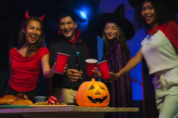 Wall Mural - Dinner and group of people celebrating together at Halloween party. Friends are happy and celebrating with food, wine and friendship of love and cheers of champagne at the event.