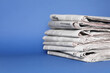 © New Africa - Stack of newspapers in different languages on blue background, space for text