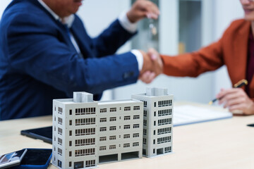 Wall Mural -  A businessman at a desk in a sales office sells a condo building to a customer. They agree to sign a contract, covering real estate investments in offices, apartments, and commercial properties.