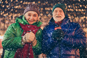 Poster - Photo two people married retired dream couple man woman enjoy x-mas christmas spirit tradition evening walk hold takeout mug beverage under advent lights wear season coats