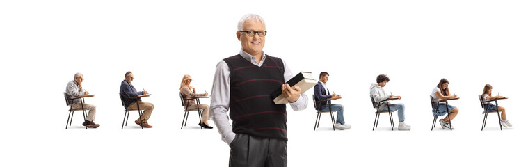 Canvas Print - Mature male teacher holding books in front of people seated in school chairs in a row