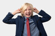 © somemeans - Portrait of a young businessman covering ears with hands and screaming