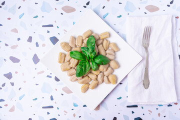 Top view of a plate of gnocchi with basil leaves.