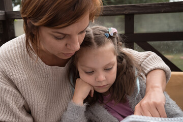 mother and daughter doing homework together outdoors