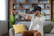 © Tetiana - A young Muslim man is sitting at home on the sofa wearing a virtual mask and emotionally gesturing with his hands watching online games