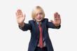 © somemeans - Portrait of a cute little boy in a blue suit showing stop gesture with both hands. Isolated on white background.