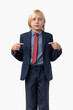 © somemeans - Blond boy in a blue suit and red tie points his fingers at himself.