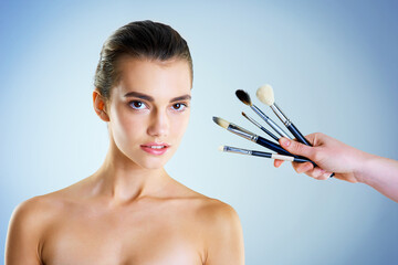 Portrait, woman and makeup brushes for beauty with makeover, pride and dermatology on studio backdrop. Female person, cosmetic tools and skincare for glow, wellness and confidence in blue background