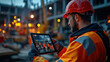 © khonkangrua - A construction worker in a hard hat and safety vest uses a tablet on-site, demonstrating the integration of technology in construction.