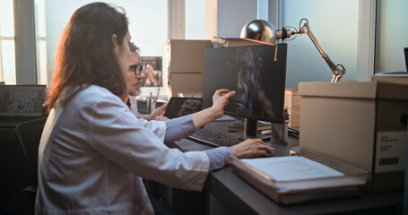 two diverse scientists discuss 3d visualization of ancient human head anatomy displayed on pc and ta