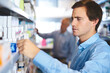 © StarDweller/peopleimages.com - Man, reading and customer in pharmacy for medicine, shopping and medical product with prescription. Male person, shelf and check label in chemist for health supplements, choice and healthcare pills