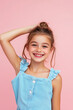 © wolfhound911 - Lovely girl with her arm raised to her head, wearing trendy blue attire, smiling sweetly on a pink background.