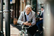 © Marko Geber - Middle aged businessman with smartphone commuting in city with bike