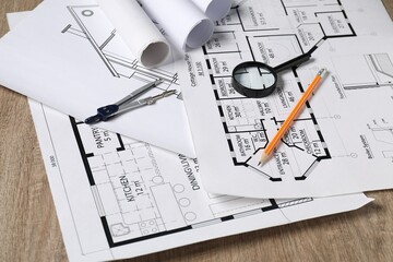 Poster - Different engineering drawings, dividers, pencil and magnifying glass on wooden table, closeup