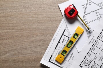 Canvas Print - Different engineering drawings, building level and measuring tape on wooden table, flat lay. Space for text