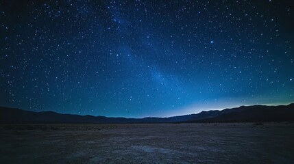 Wall Mural - a serene night sky filled with stars over a vast, dark landscape.