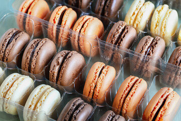 Wall Mural - Table top view of a package of a variety of flavored French macarons. White, milk and dark chocolate with orange flavors.