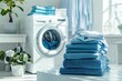 © LidiaLens - Fresh and organized laundry room with a stack of neatly folded blue clothes, modern washing machine, and soft natural light creating a calm and tidy atmosphere