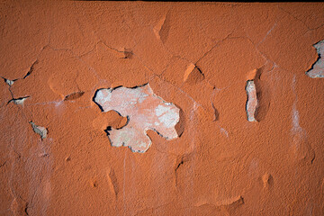 A photo of peeling paint on the wall.Old orange plaster.Restoration of the facade of the building.The old house.