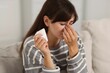© New Africa - Woman with napkin suffering from sinusitis on sofa at home