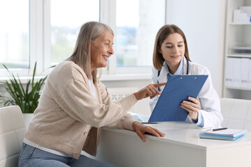 Poster - Smiling healthcare worker and senior patient checking clipboard with analysis results in hospital