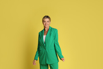 Canvas Print - Beautiful woman in stylish green suit on yellow background