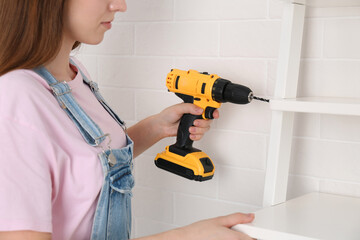 Wall Mural - Woman with electric screwdriver assembling furniture indoors, closeup