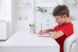 © New Africa - Boy with correct posture doing homework at white desk indoors