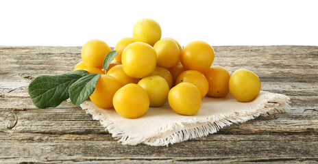 Sticker - Pile of fresh plums and green leaves on wooden table against white background