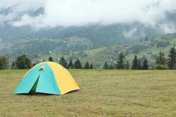 Poster - Camping tent on green grass in mountains, space for text