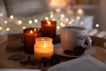 Wall Mural - Burning candles, lights, coffee and decor on bed indoors, closeup. Autumn atmosphere