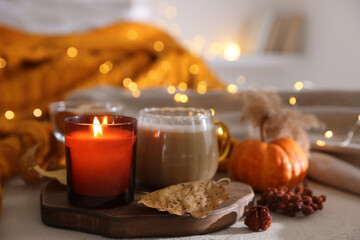 Wall Mural - Burning candle and autumn decor on light table, closeup. Cozy atmosphere