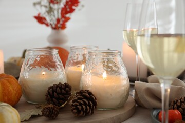 Wall Mural - Burning candles, glasses of wine and autumn decor on table, closeup