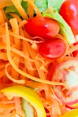 Wall Mural -  A bright and fresh salad with thinly shredded carrots, cherry tomatoes, sliced ​​red tomatoes, greens (probably romaine lettuce) and sliced ​​yellow bell pepper. The textures are distinctly different