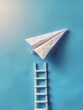 © SashaMagic - Paper plane above a ladder on a blue background.