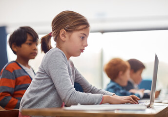 Laptop, kids and girl in classroom for online project with growth, child development and web education. Typing, elearning and school students with exam course for research, notes and children at desk