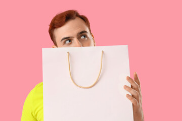 Canvas Print - Young man with shopping bag on pink background