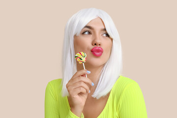 Sticker - Portrait of beautiful young woman in wig with lollipop on beige background