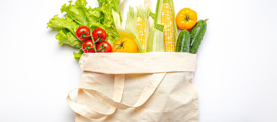 Vegetarian grocery shopping. Different fresh vegetables in a textile shopper bag on white background, healthy vegan food from supermarket or delivery concept..