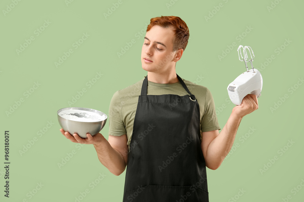 Male confectioner preparing meringue with mixer on green background