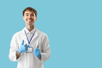 Wall Mural - Male dentist with electric toothbrush showing thumb-up on blue background