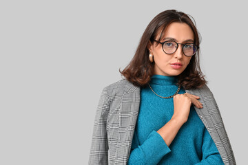 Canvas Print - Fashionable young woman with stylish jewellery and eyeglasses on grey background