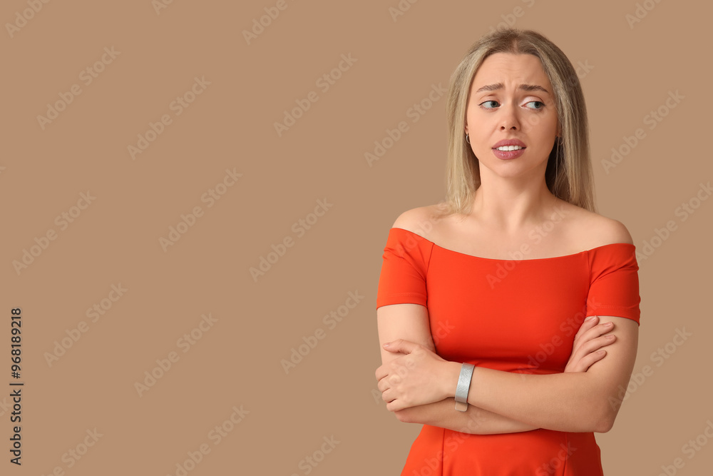 Embarrassed young woman on beige background