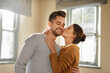 © Chanelle2000/peopleimages.com - Home, couple and hug with kiss for love, affection and bonding together in marriage in house. Happy people, woman and man with cheek embrace for admiration, commitment and connection in relationship