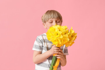 Wall Mural - Cute little happy boy with bouquet of beautiful narcissus on pink background