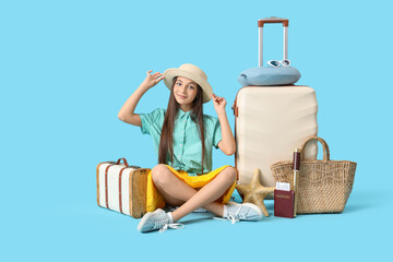 Poster - Cute little tourist with bags and travel accessories sitting on blue background