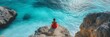 © StockUp - A person in a vibrant red dress sits peacefully on a cliff overlooking a clear turquoise sea, embodying tranquility and escape.