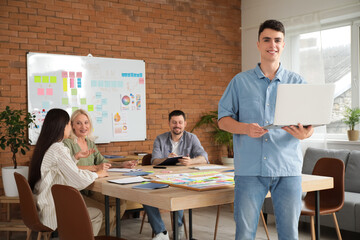 Sticker - Young man with laptop and his colleagues working on business plan in office